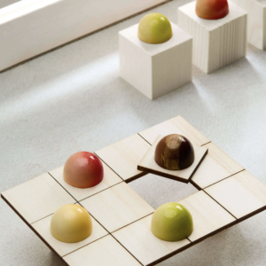 Bonbons en chocolat colorés présentés sur des supports blancs et en bois.